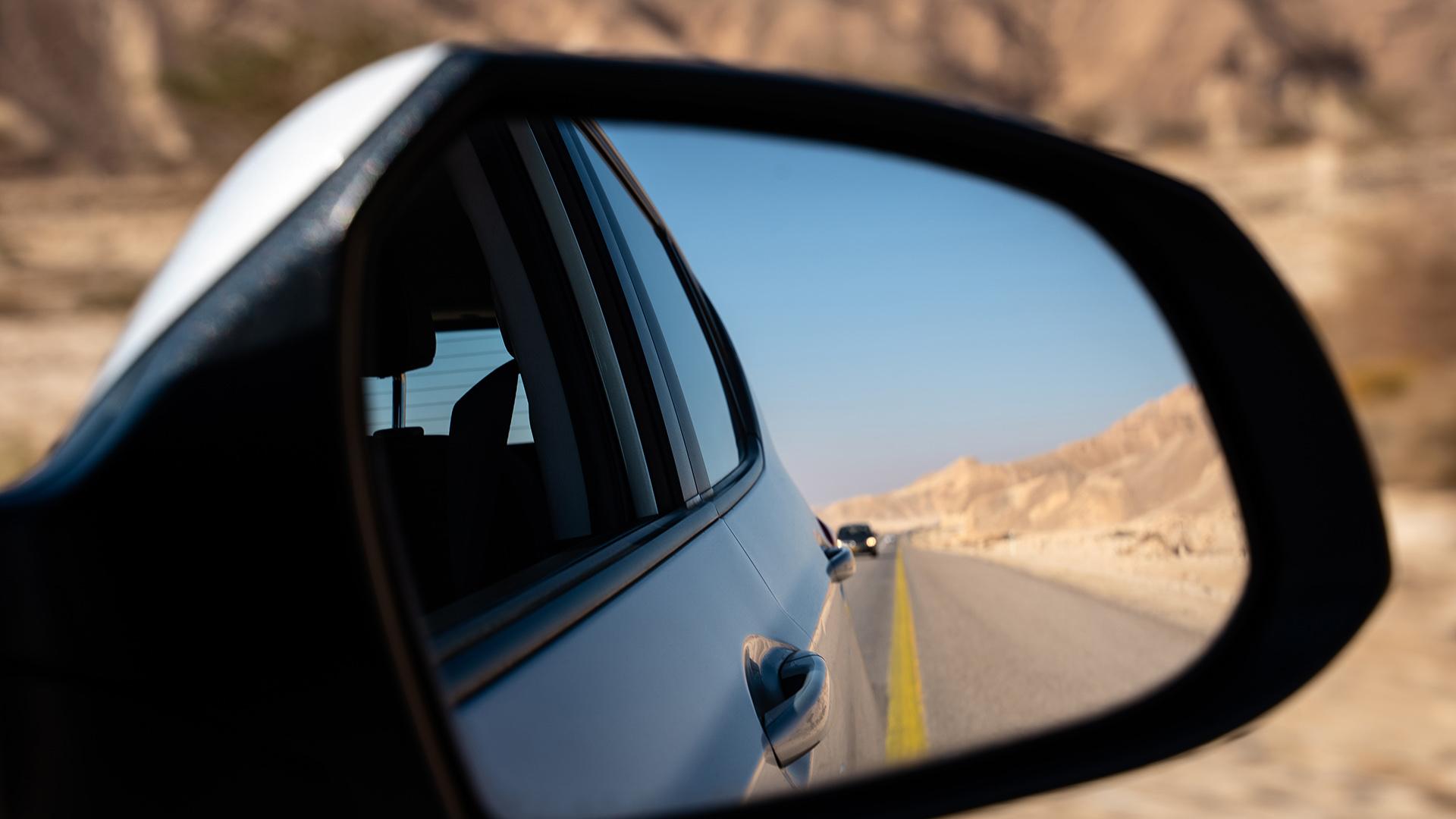 Street, desert and car seen from the rearview mirror
