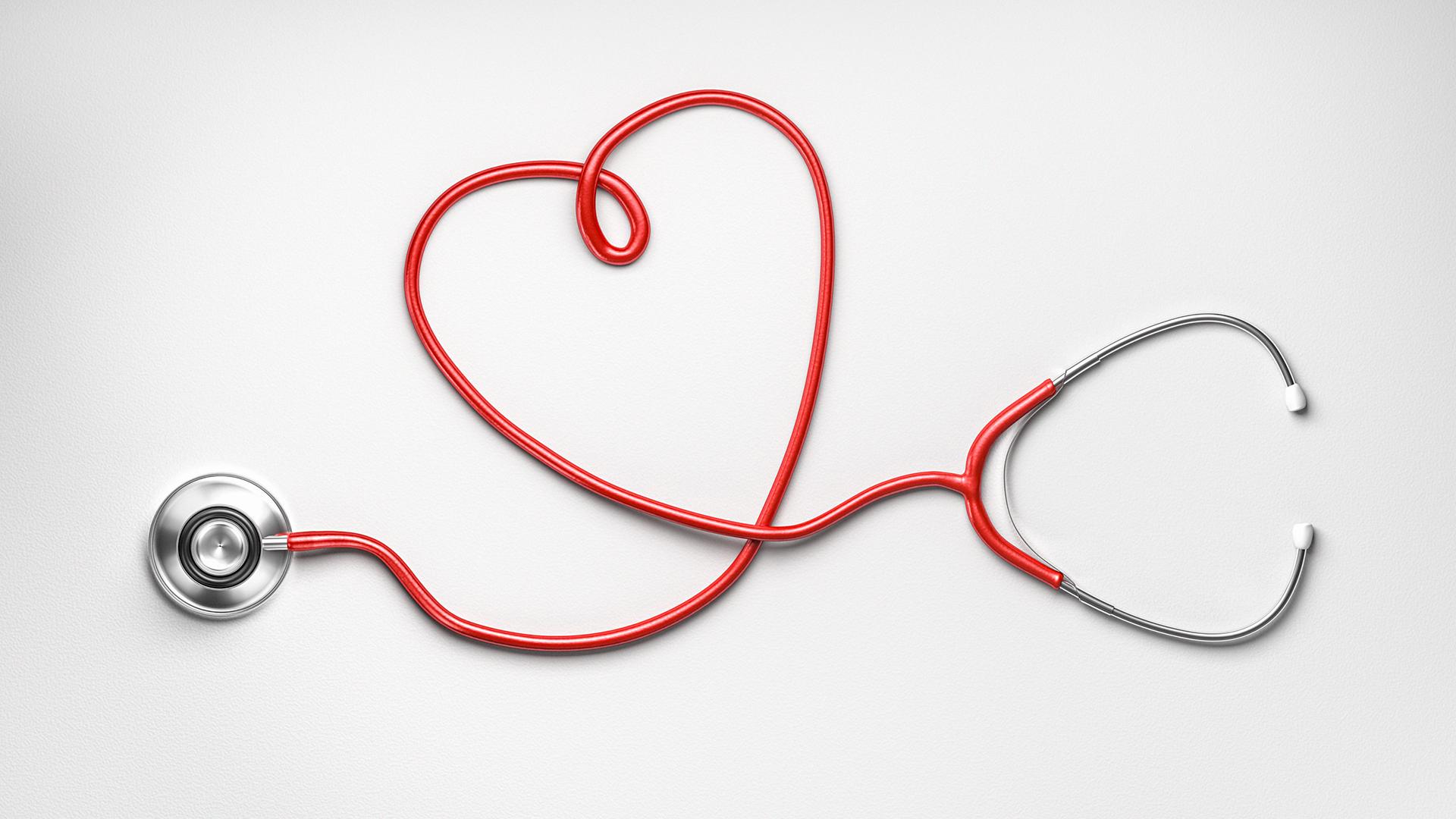 A stethoscope on a white background with the red cable making a heart shape in the centre