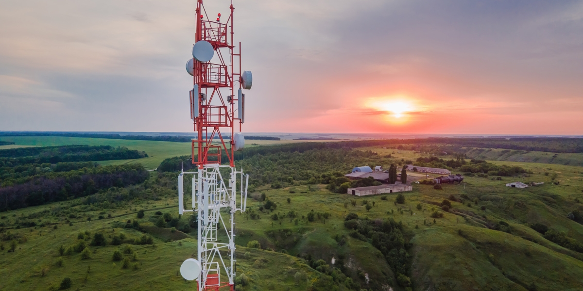 Red satellite tower with a sunset and green hills