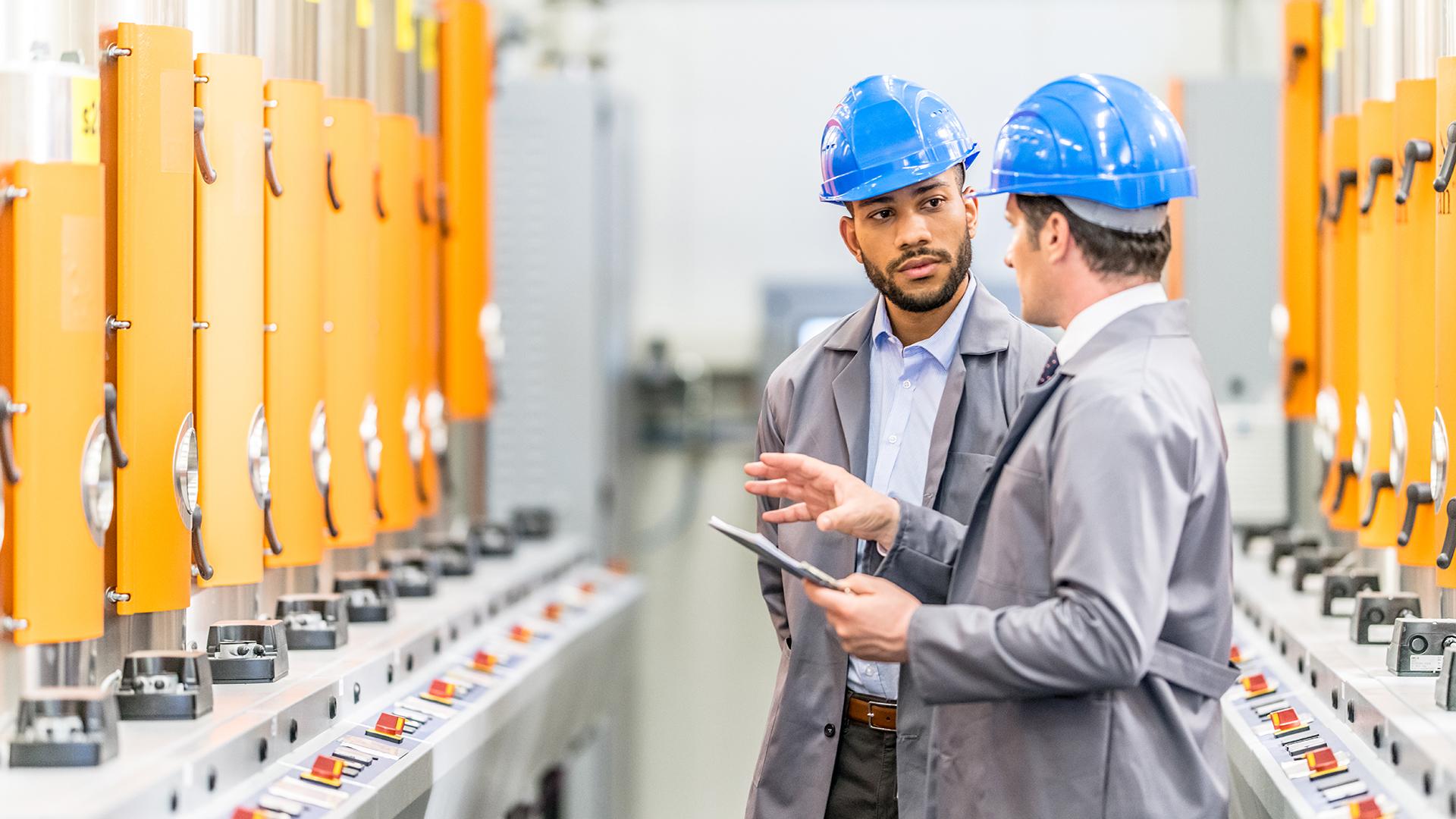 Engineers talking while inspecting machinery - stock photo