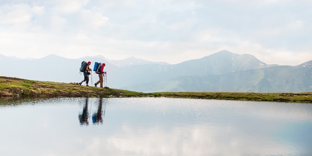 Hikers on mountain with reflection in lake
