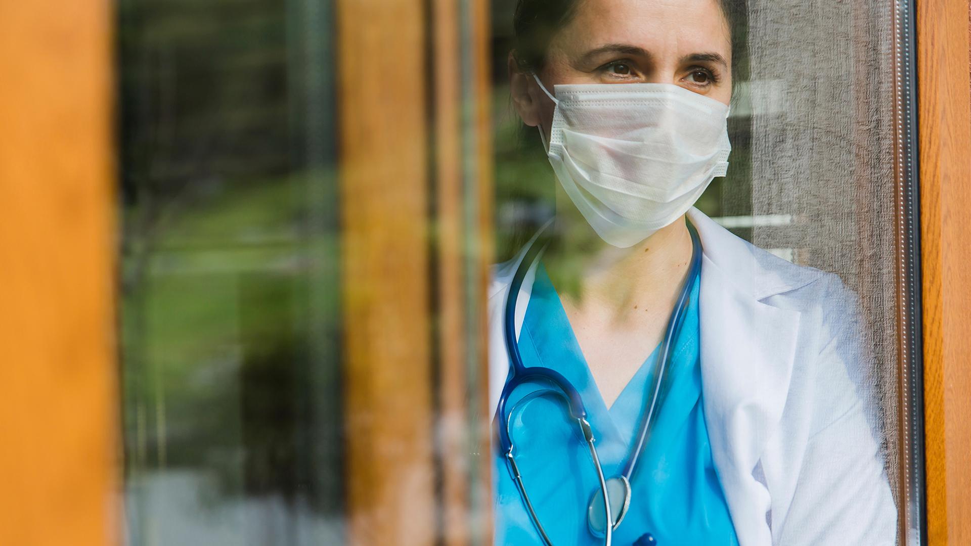 Female doctor looking through window at hospital
