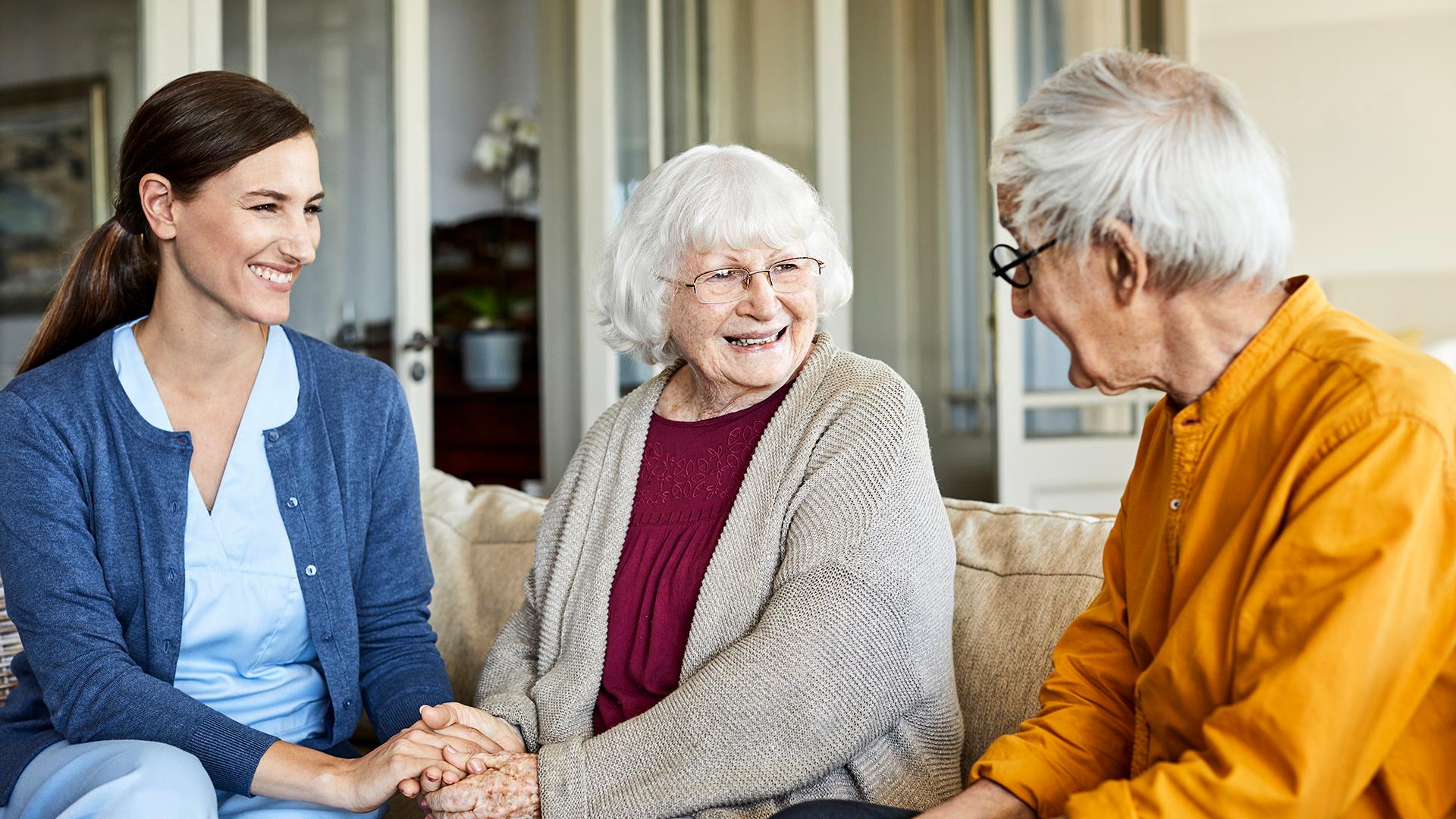 Smiling nurse with elderly couple at home