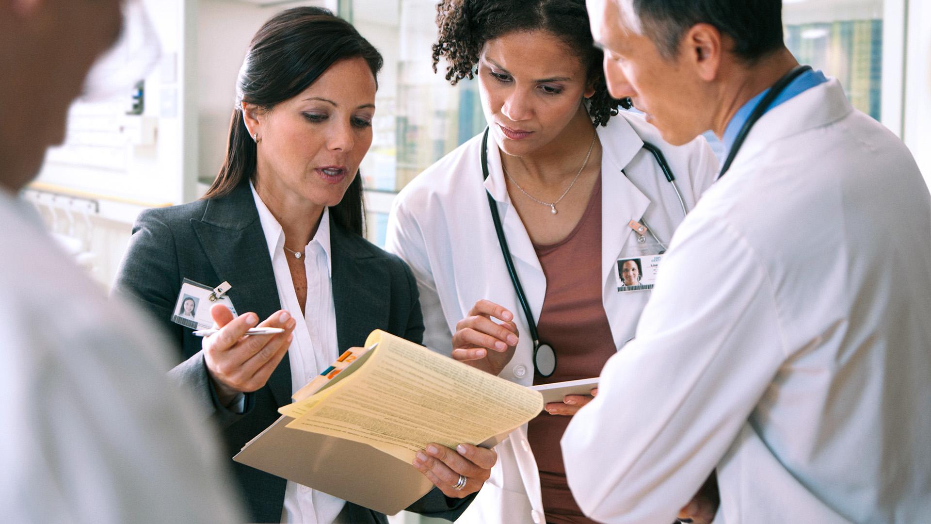 A hospital professional discussing documents with doctors.