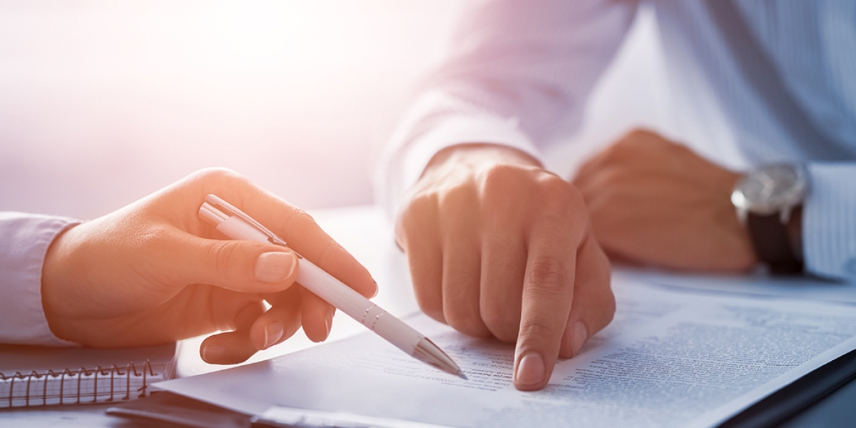 The hands of two professionals pointing to a section of a legal document.