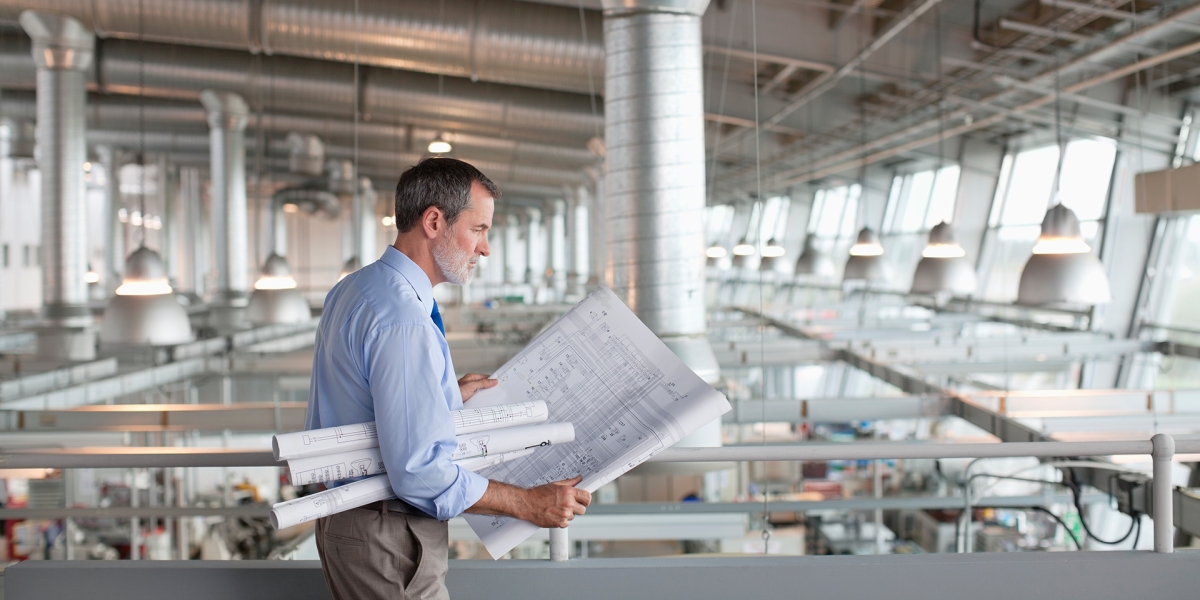 Architect viewing a blueprint in an industrial building