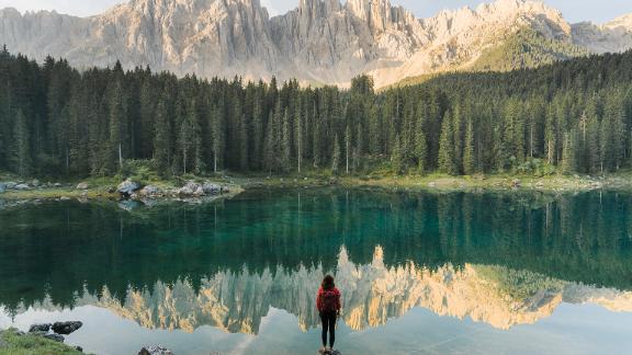 Woman standing and looking at Lago di Carezza in Dolomites