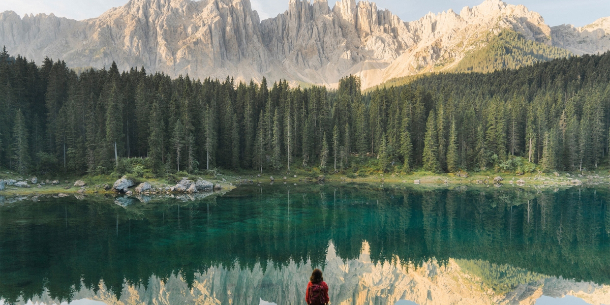 Woman standing and looking at Lago di Carezza in Dolomites