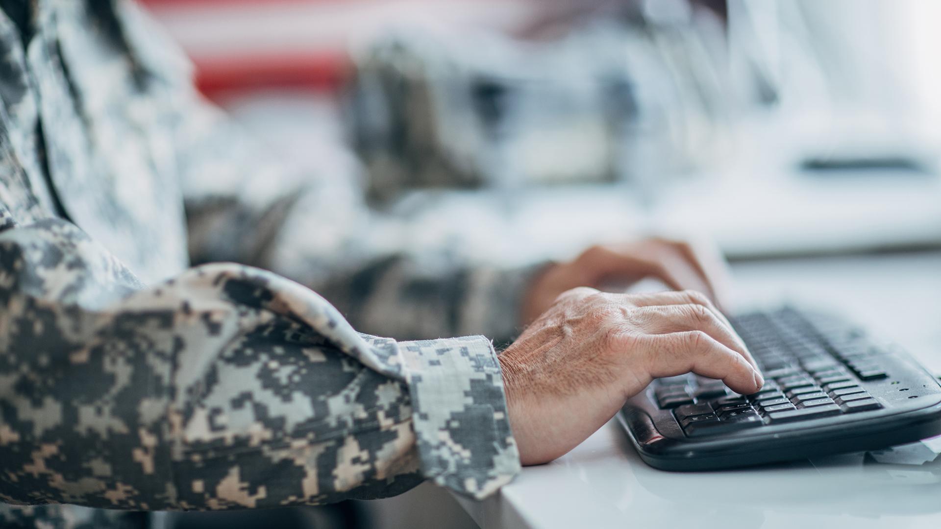 Top view of american soldier in military uniform typing on the computer. USA internet and network security. - stock photo