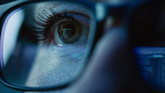 A close up of a persons eyes behind a pair of glasses.