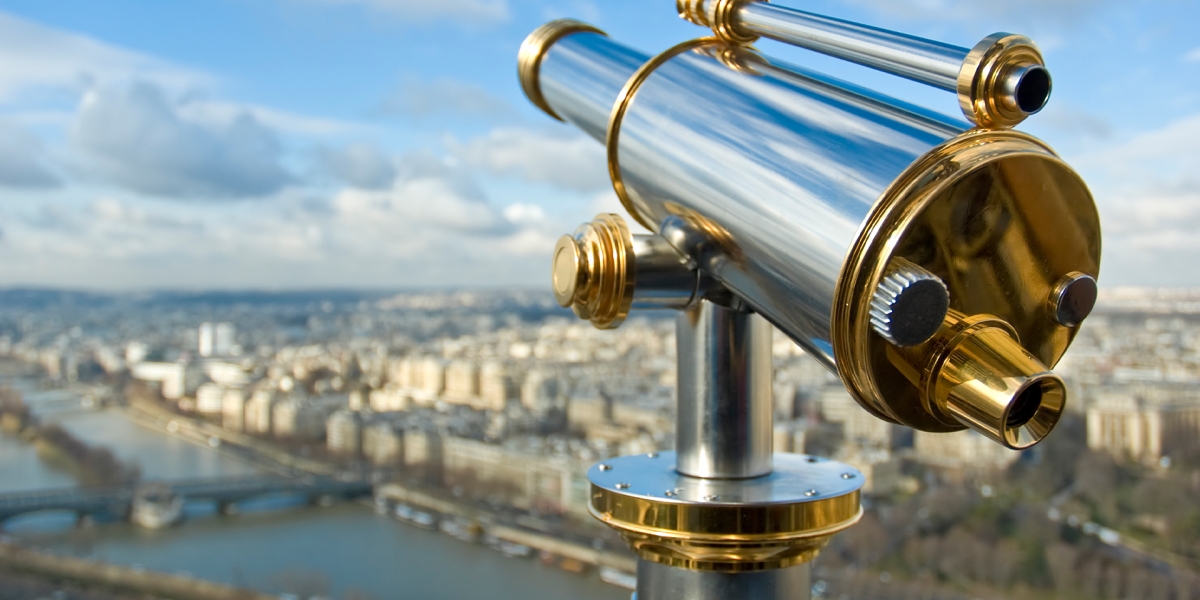 Gold and silver telescope pointed over a cityscape with a river