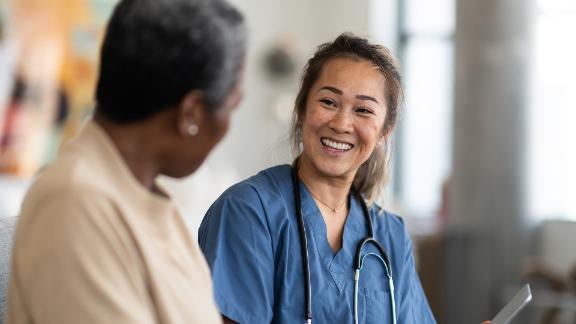 A smiling physician speaking with her senior patient.