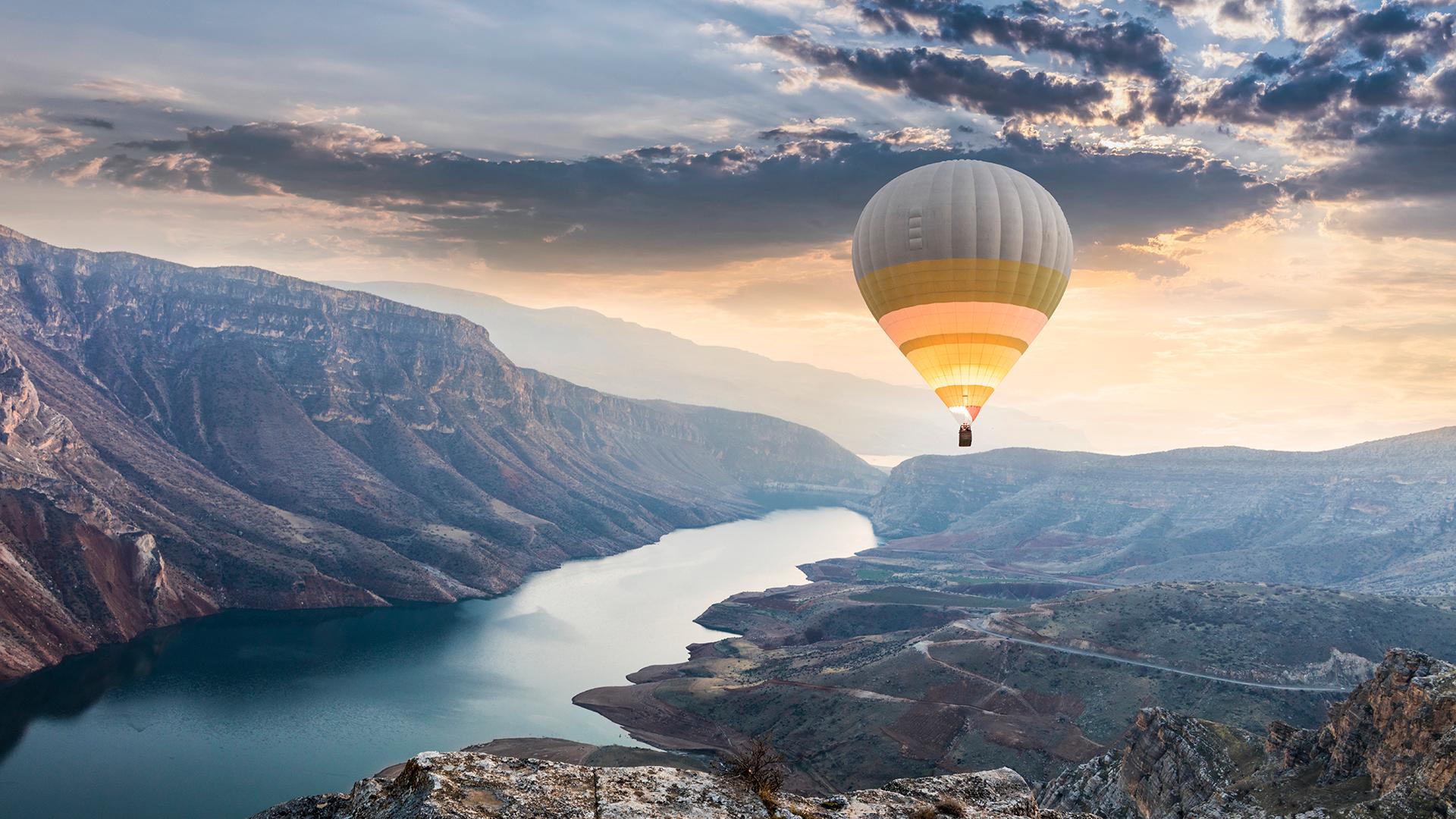 Hot air balloon flying over a Turkish mountain range.